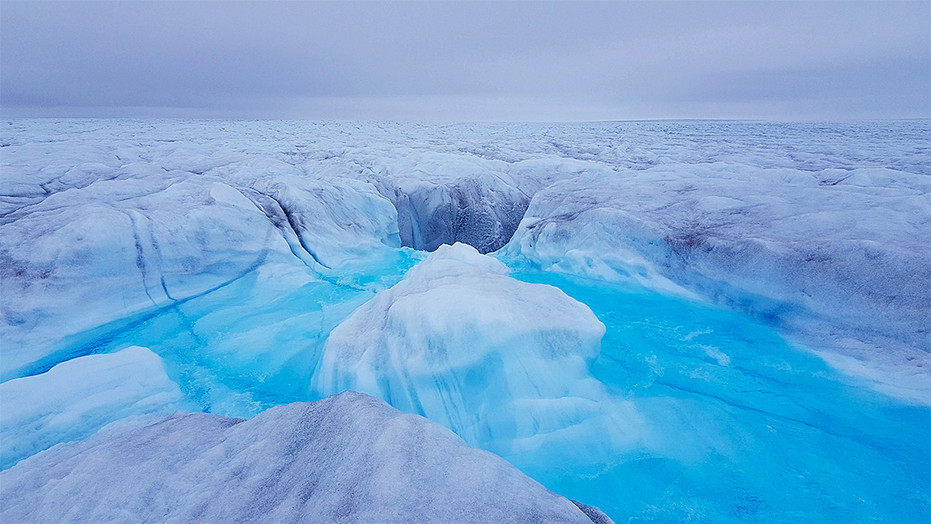 Water flows into a moulin on the surface of the Store Glacier in Greenland.
